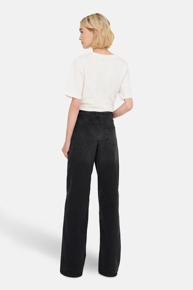 Wijde zwarte denim jeans van JDY, van achteren getoond, met een crèmekleurig T-shirt.