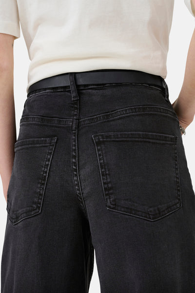 Jeans larges noirs de JDY, vus de dos avec une ceinture noire et un T-shirt blanc.
