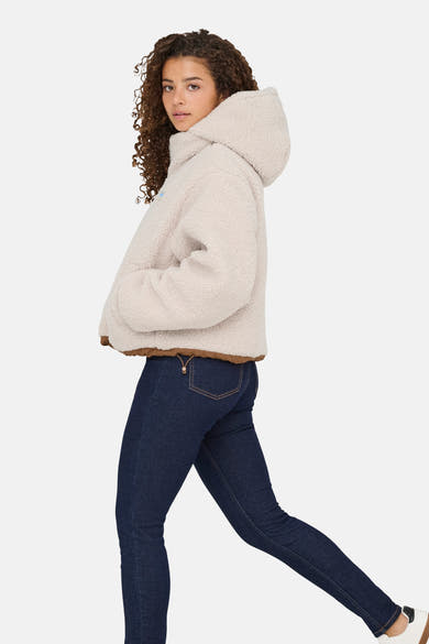 Ecru korte jas van ONLY, met capuchon en bruine bies, gedragen met een donkerblauwe jeans.
