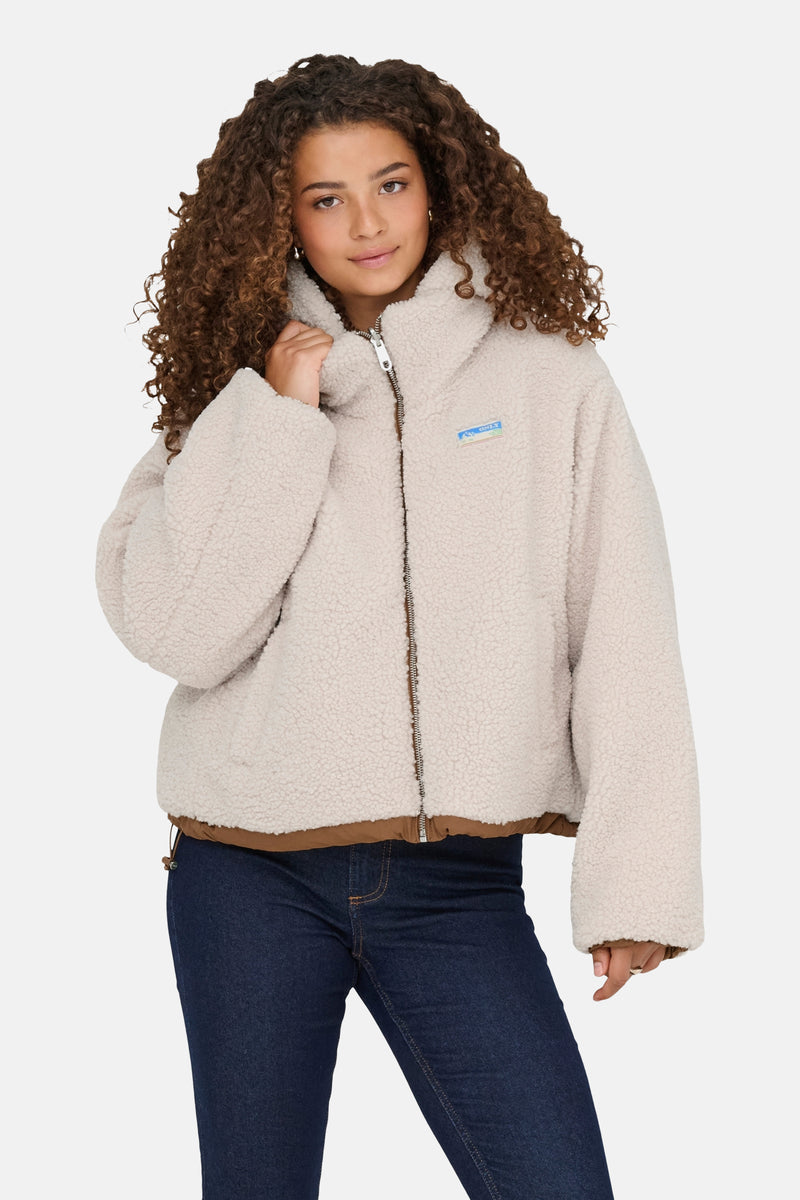 Veste courte écru de ONLY, en imitation peau de mouton, portée avec un jean bleu foncé