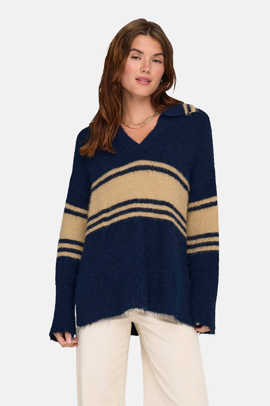 Pull bleu à rayures contrastantes de ONLY, porté avec un pantalon clair et un collier doré.
