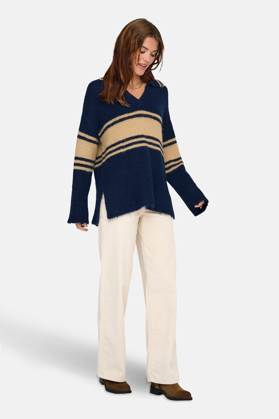 Pull bleu rayé en maille, par ONLY, porté avec un pantalon en velours côtelé et des bottines marron.
