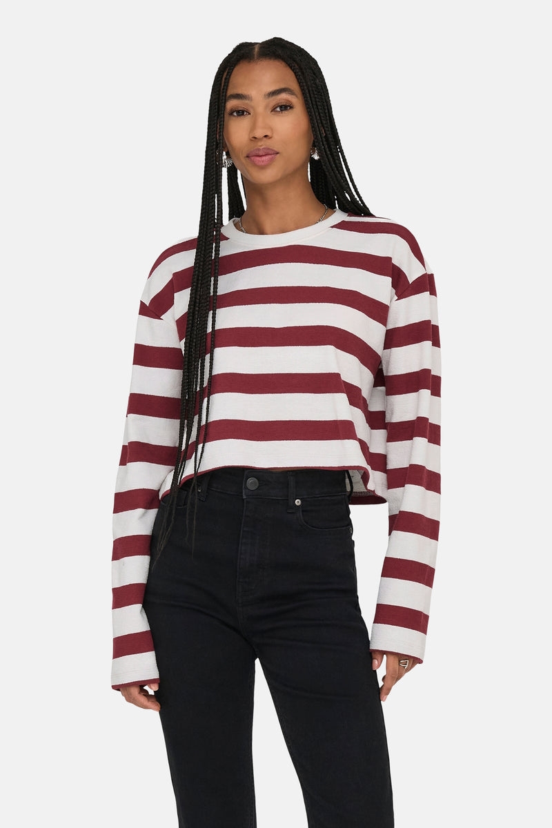 Sweat-shirt bordeaux à rayures blanches de ONLY, porté avec un jean noir taille haute et des boucles d'oreilles pendantes.
