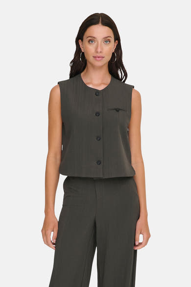 Gilet brun par ONLY, avec boutons décoratifs et une petite poche, porté avec un pantalon assorti.
