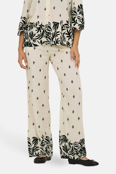 Ecru broek van JDY, met zwart bloemenpatroon, rechte pasvorm en zwarte platte schoenen.