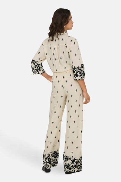 Ecru broek van JDY, met zwarte bloemenprint, wijde pasvorm en elastische tailleband, van achteren gezien.