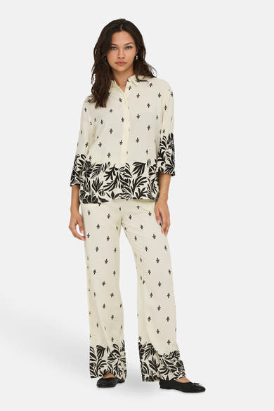 Ecru blouse met lange mouwen van JDY met zwart bladmotief, gedragen met een bijpassende broek en zwarte ballerina's.