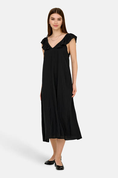 Robe noire à volants de JDY avec un motif rayé vertical, portée avec un collier argenté et des ballerines noires.