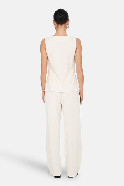 Gilet blanc van JDY, présenté de dos, porté avec un pantalon assorti et des boucles d'oreilles créoles.