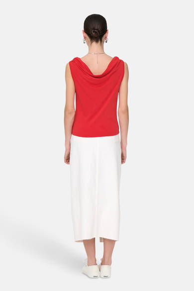 Top rouge sans manches de JDY, porté avec une jupe blanche et des chaussures de sport.