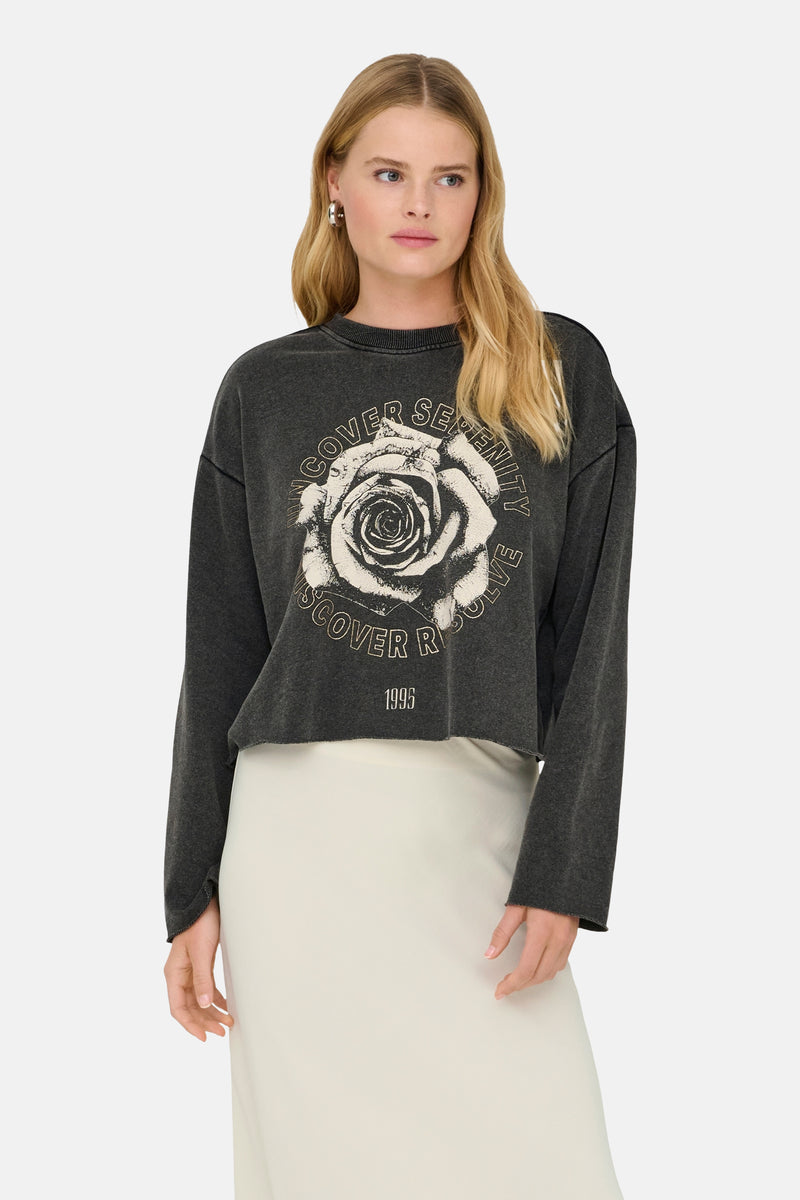 Zwarte rondehals sweatshirt van ONLY®, roze print met opschrift, gedragen met een lange ivoorkleurige rok en bruine pumps.