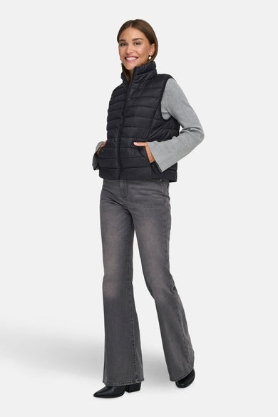 Veste sans manches noire de ONLY, portée sur un pull gris à manches longues et un jean évasé.
