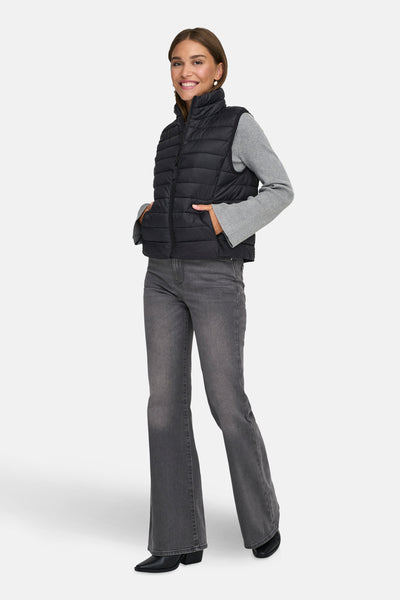 Veste sans manches noire de ONLY, portée sur un pull gris à manches longues et un jean évasé.
