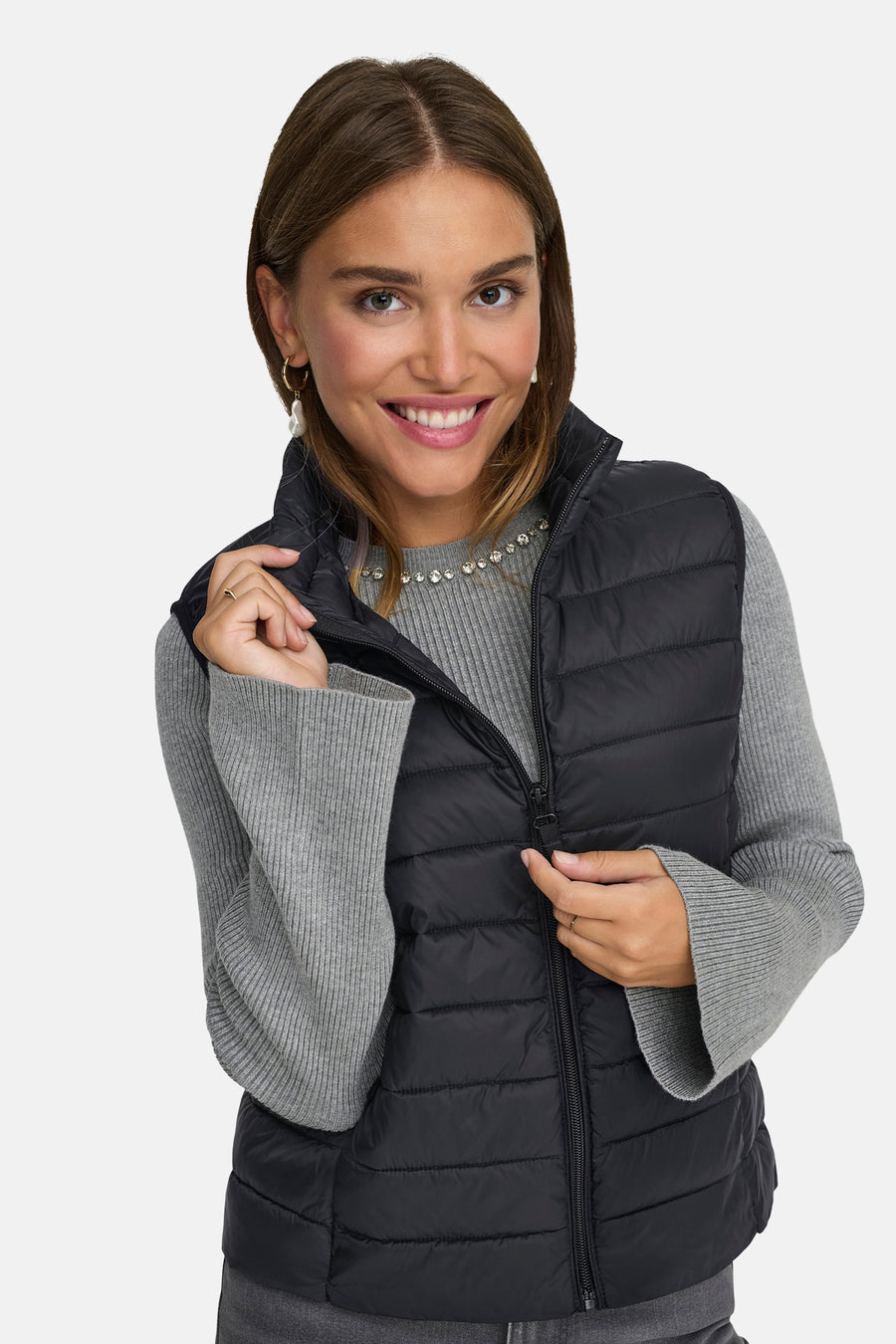 Zwart mouwloos vest van ONLY, gedragen over een grijze trui met een strass-ketting.