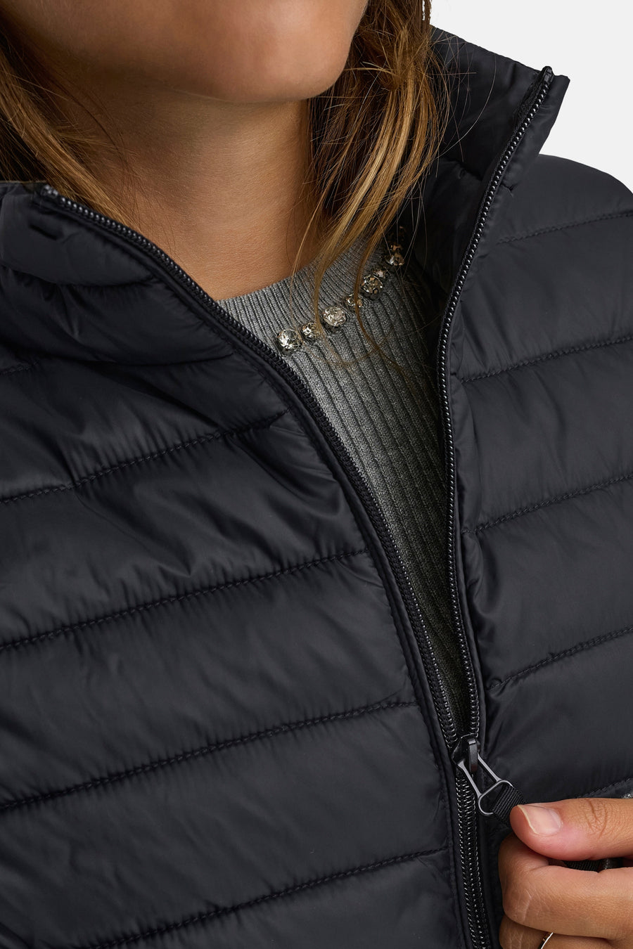 Zwart mouwloos vest van ONLY, ritssluiting aan de voorkant, gedragen over een grijze trui met een decoratieve ketting.