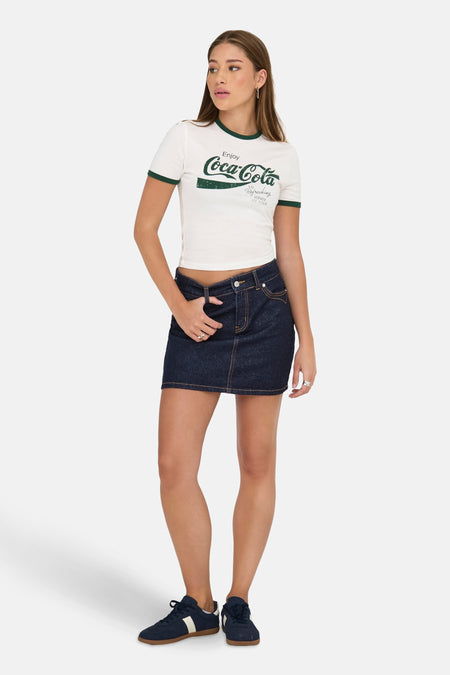 Korte donkerblauwe spijkerrok van ONLY, gedragen met een T-shirt met print en sportschoenen.