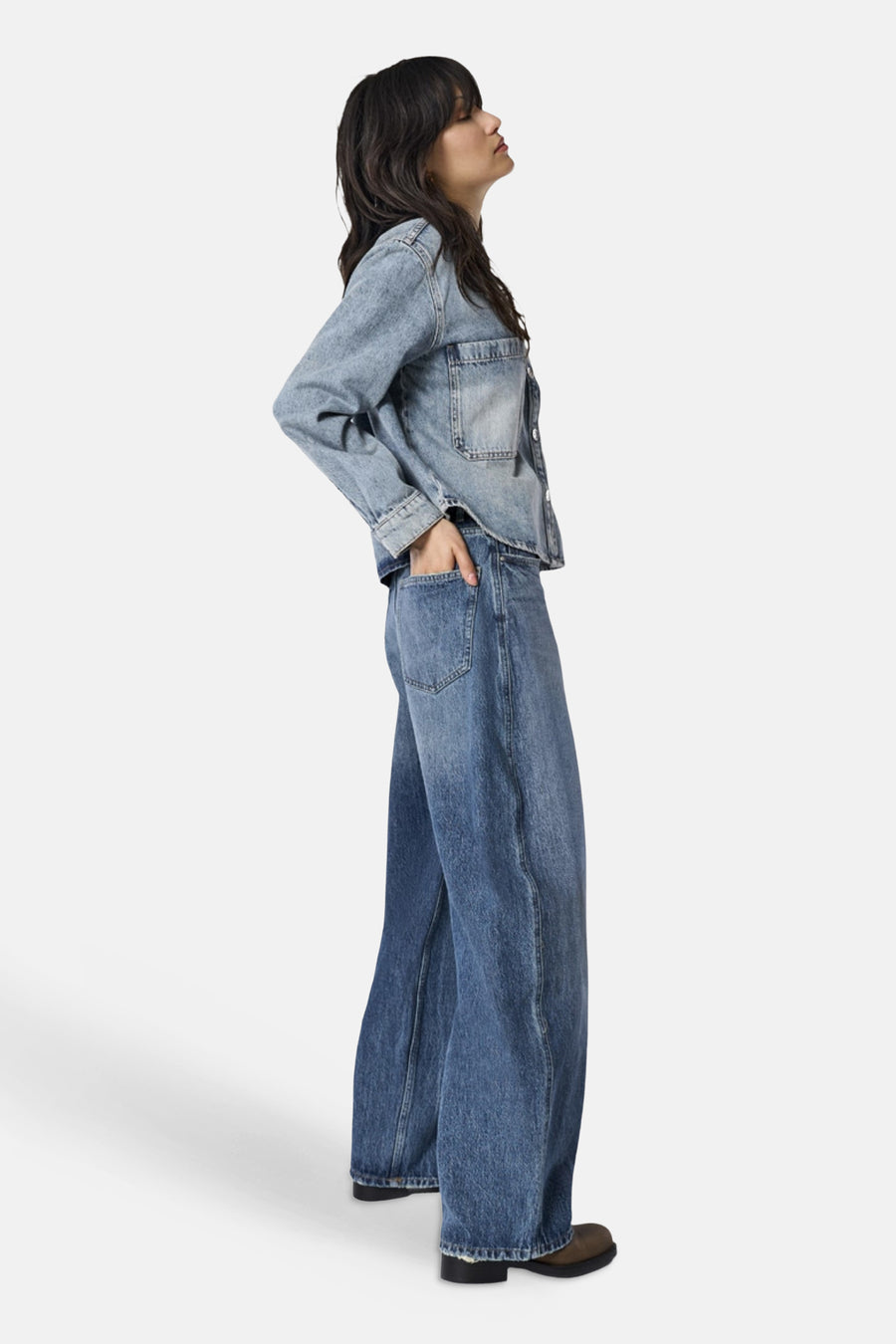 Dark blue wide-leg denim jeans by ONLY®, side view with visible front pockets and frayed hem, worn with a light wash denim jacket and brown boots.