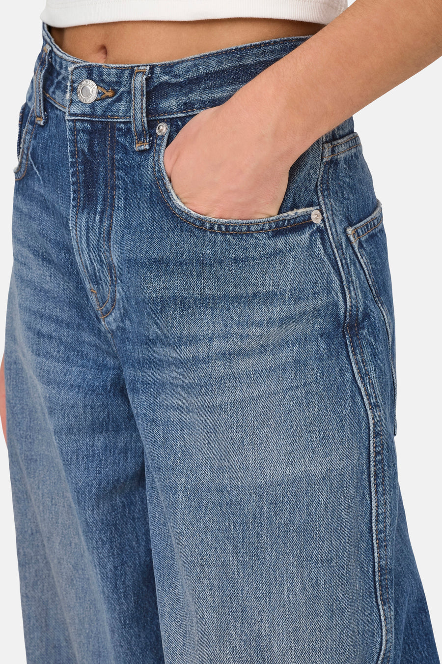 Dark blue denim jeans by ONLY® with faded wash, front pocket detail, and silver button closure, shown in close-up side view.