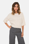 Beige ronde hals trui van ONLY®, ribgebreid, gedragen met een gestreepte broek.