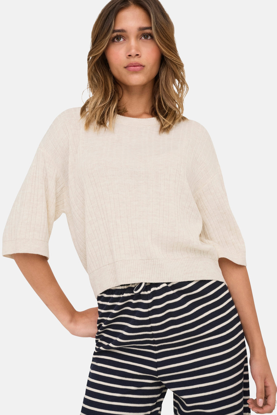Beige ronde hals trui van ONLY, gedragen met een marineblauwe en witte gestreepte broek.