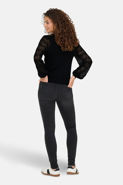 Zwarte trui van ONLY, met kanten mouwen en een aansluitende pasvorm, gedragen met een donkere skinny jeans en sneakers.