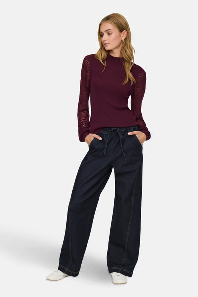 Bordeaux trui van ONLY, met kanten lange mouwen, gedragen met een high-waist spijkerbroek.