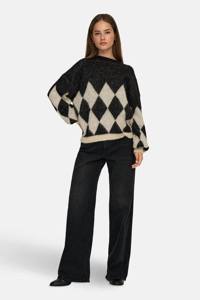 Pull à col rond multicolore de ONLY, avec motif losanges et manches longues, porté avec un jean noir.
