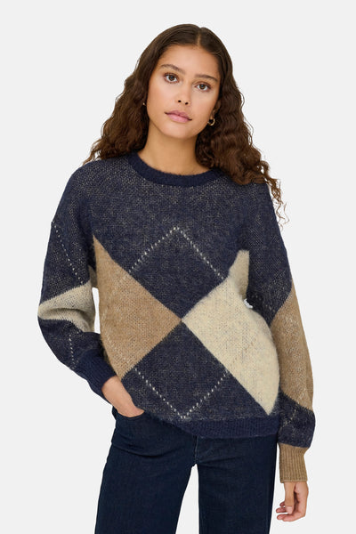 Multikleuren trui met ruitpatroon van ONLY®, gedragen met een donkere jeans en gouden oorbellen.