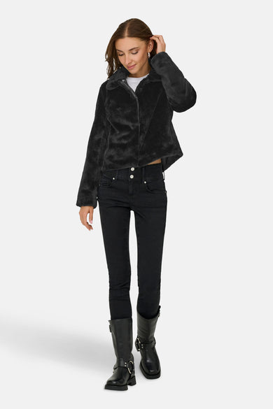 Veste courte noire en fausse fourrure de JDY, portée avec un jean noir et des bottes motardes.