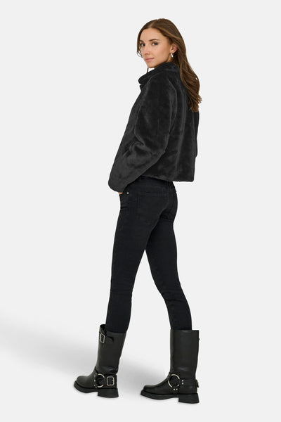 Veste courte noire de JDY, avec une texture douce et un style décontracté, portée avec un jean et des bottes noires.