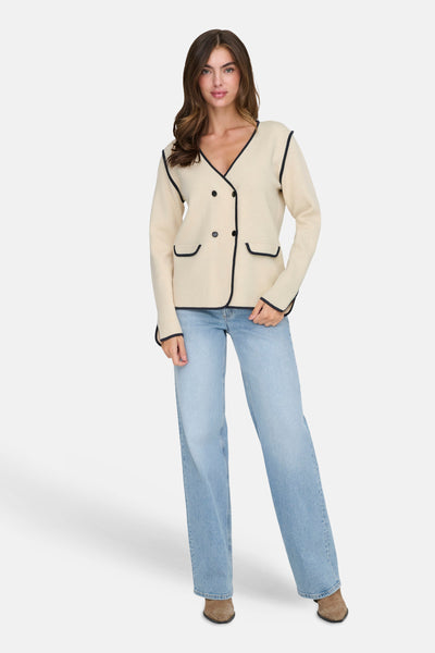 Beige double-breasted blazer van JDY, met contrasterende zwarte bies en opgestikte zakken, gedragen met een spijkerbroek en enkellaarsjes.