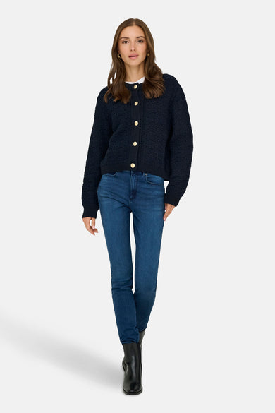 Marineblauwe cardigan van JDY, met gebreide textuur en knopen, gedragen met een spijkerbroek en zwarte enkellaarsjes.