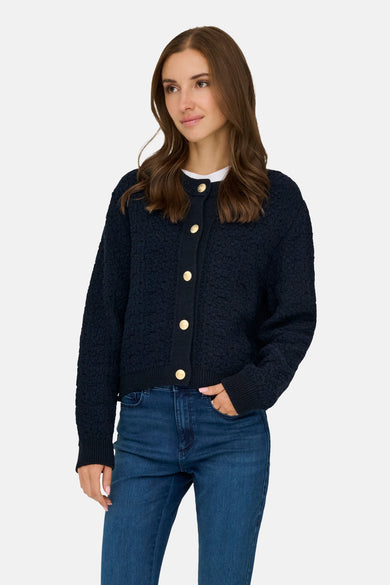 Blauwe textuurcardigan van JDY, gedragen met een blauwe jeans en een wit T-shirt.
