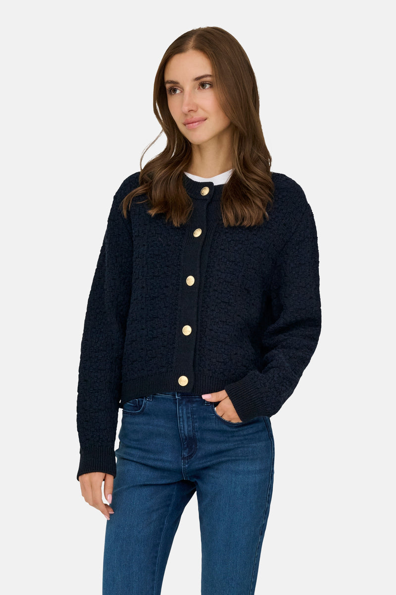 Blauwe textuurcardigan van JDY, gedragen met een blauwe jeans en een wit T-shirt.