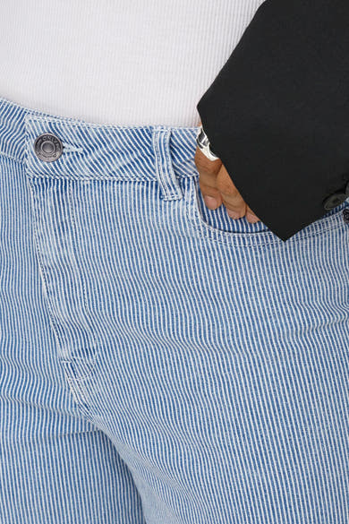 Pantalon en denim bleu clair par ONLY, à rayures verticales et détail de poche avec une main et une bague visible.