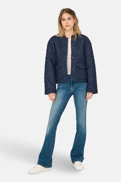 Kort donkerblauw spijkerjack van ONLY®, doorgestikt model gedragen met een blauwe jeans en witte sneakers.