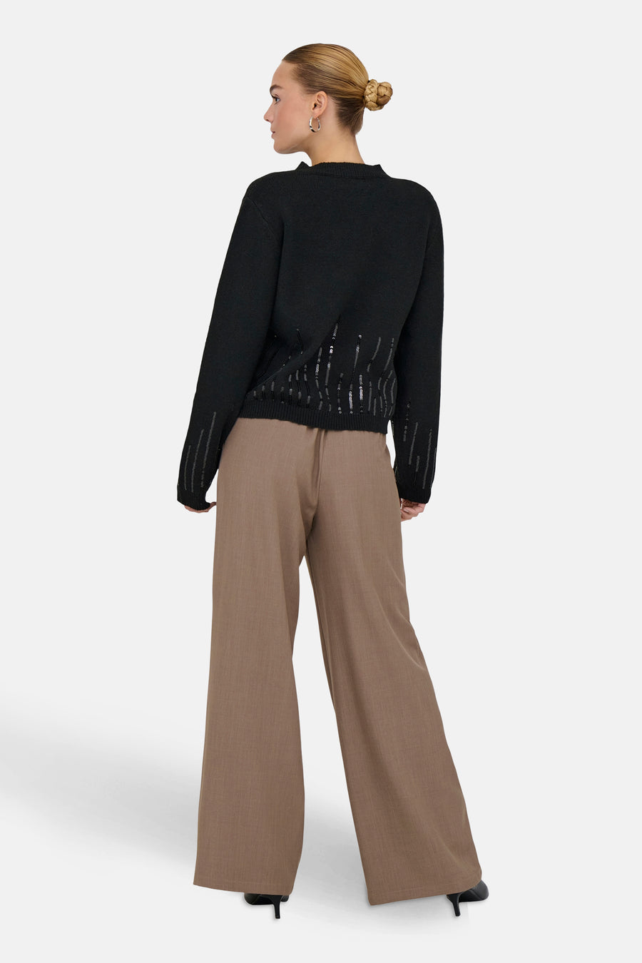 Pull à col rond noir de JDY avec des détails pailletés verticaux et porté avec un pantalon marron ample.