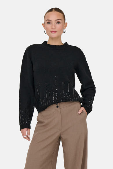 Pull à col rond noir par JDY avec des motifs de sequins et porté avec un pantalon marron.
