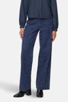 Gekleurde blauwe jeans van JDY, met wijde pijpen en gespikkeld patroon, gedragen met een blauw overhemd en zwarte enkellaarsjes.