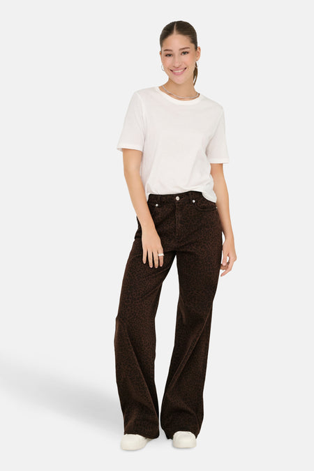 Jean coloré brun de ONLY, avec un motif animalier foncé, porté avec un t-shirt blanc et des baskets blanches.