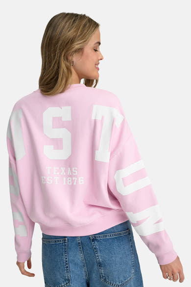 Sweat rose col rond de ONLY, imprimé "Texas est 1876" au dos, porté avec un jean taille haute.
