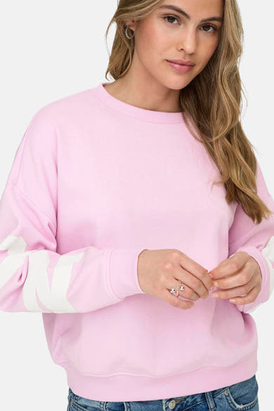 Sweat rose à col rond de ONLY, avec un motif blanc sur les manches et porté avec un jean