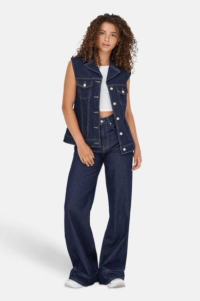 Mouwloos donkerblauw spijkerjack van ONLY, gedragen over een witte top en een bijpassende broek.
