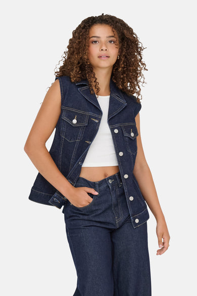 Mouwloos donkerblauw spijkerjack van ONLY, gedragen over een witte tanktop, met een bijpassende broek.