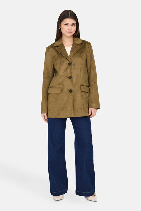 Lange bruine jas van ONLY®, gedragen met een wijde jeans en beige naaldhakken.