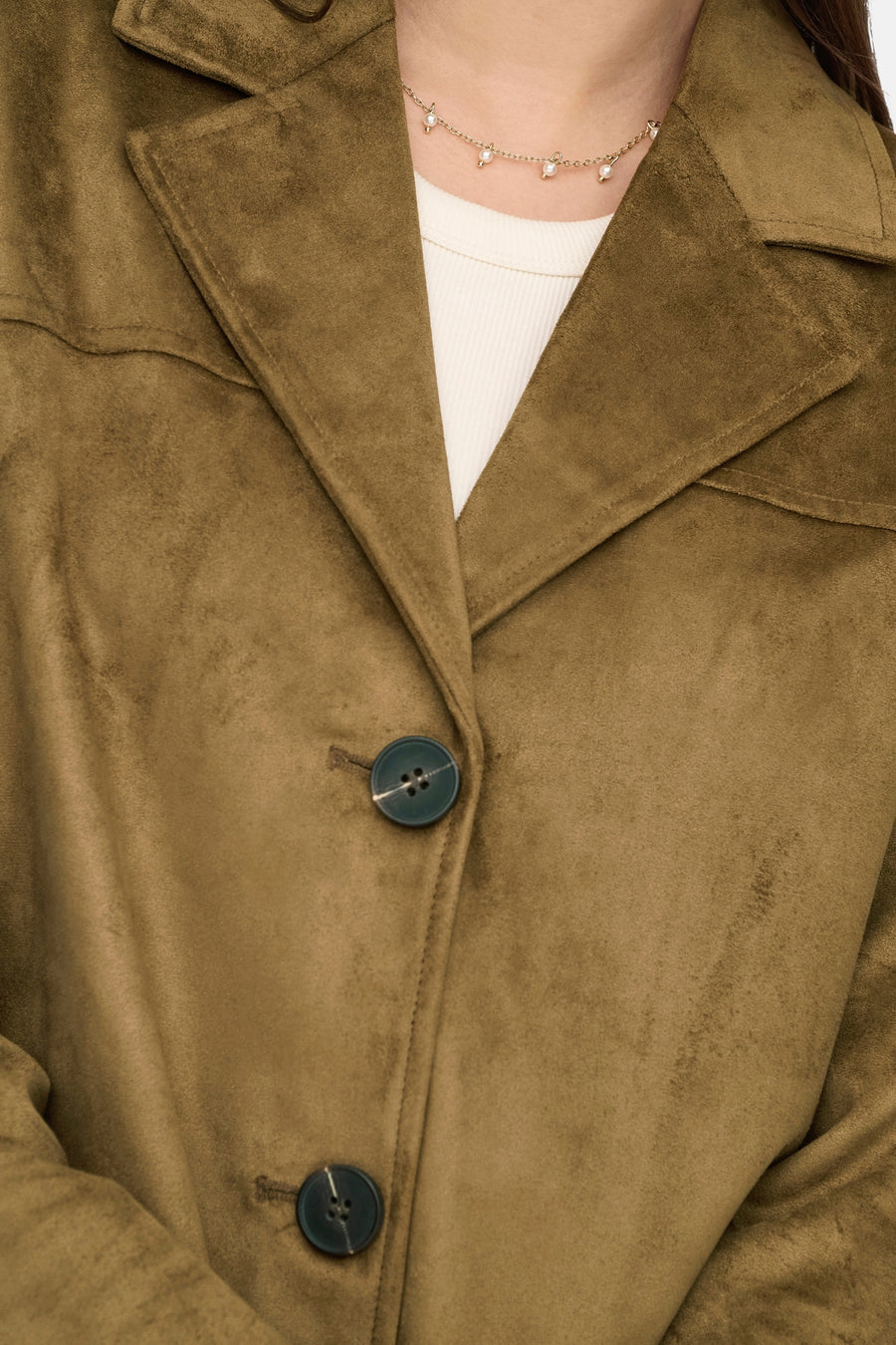 Lange bruine suèdejas van ONLY, met donkergroene decoratieve knopen en delicate ketting.