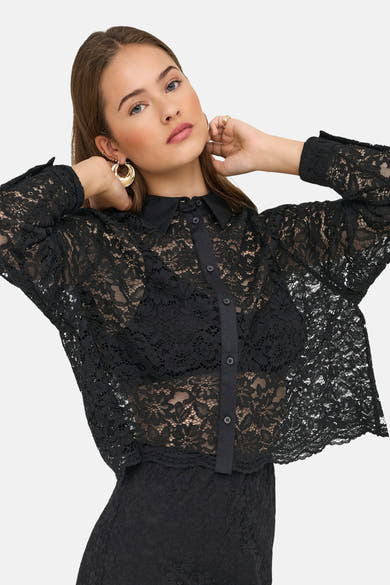 Zwarte kanten blouse van ONLY, gedragen met een zichtbare zwarte beha en gouden oorbellen.
