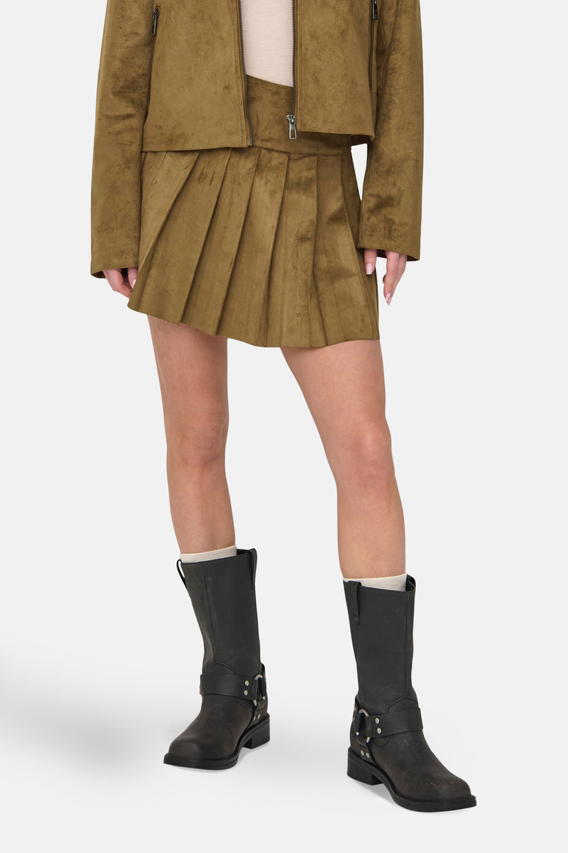 Bruine korte bruine rok, van ONLY®, geplooid met een suède textuur en gedragen met zwarte laarzen.