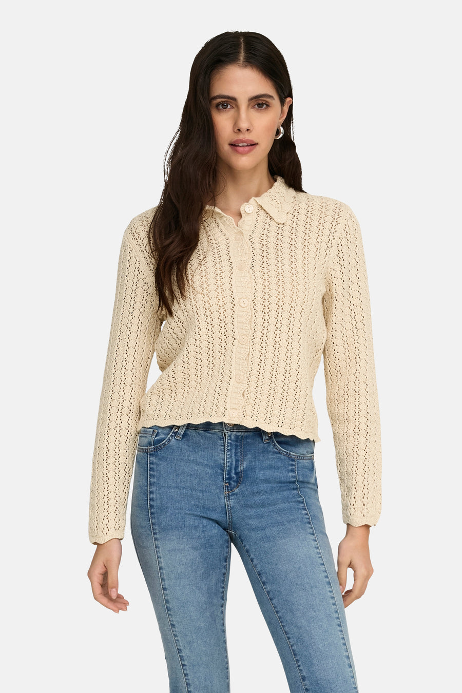 Cardigan écru en maille ajourée de JDY, porté avec un jean bleu délavé et des boucles d'oreilles argentées.
