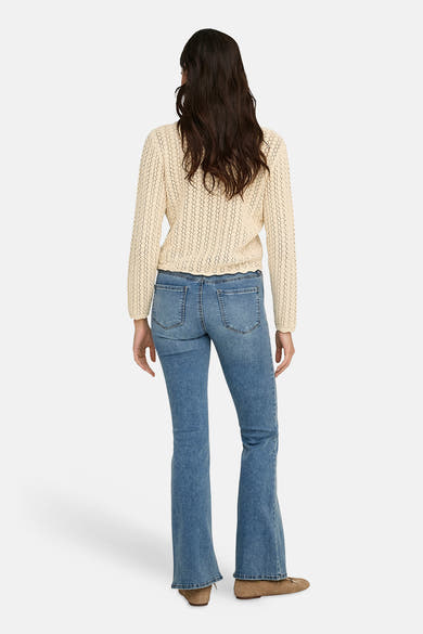Cardigan écru par JDY, avec une texture ajourée et porté avec un jean évasé.